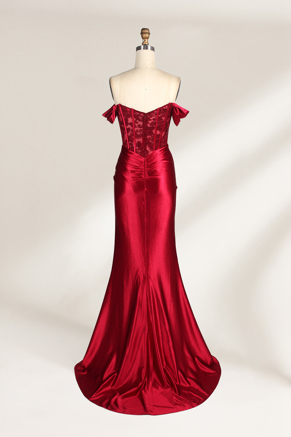 Against a light - hued backdrop, a mannequin displays a strapless red satin gown. It boasts off - shoulder ruffled sleeves, a lace - detailed bodice, and a high side slit. The ruched satin skirt and sequin - adorned top exude charm, suitable for formal dinners or galas.2