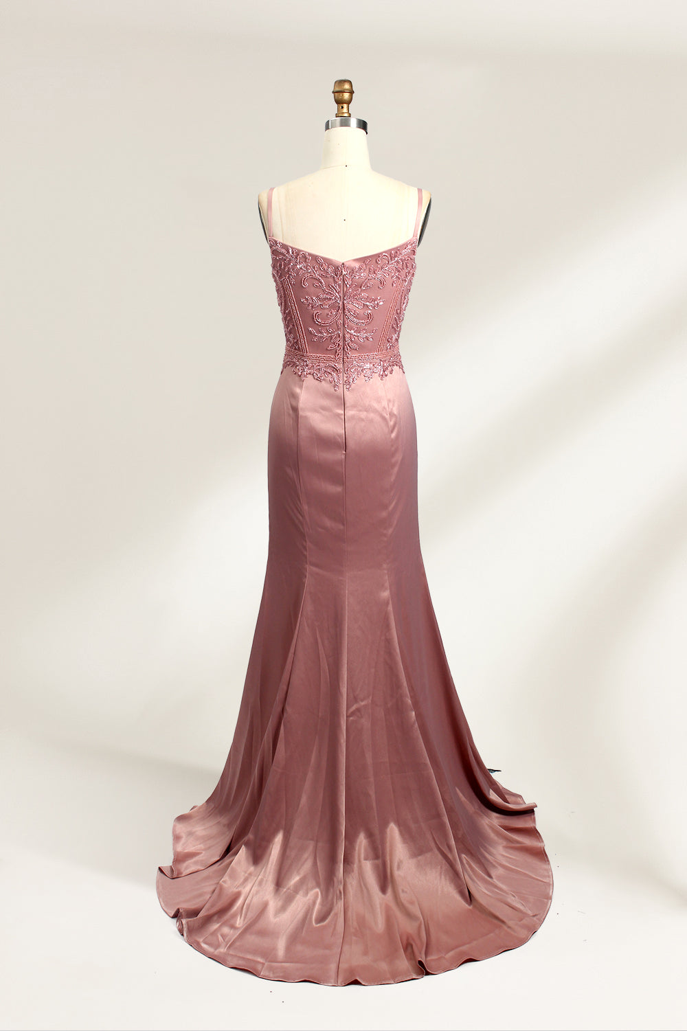 A photograph of a model mannequin wearing a floor-length, mauve satin gown with a deep V-neckline. The bodice is adorned with intricate lace detailing, featuring floral patterns and a subtle sheen. The gown has a thigh-high slit on the right side, adding a touch of elegance. The mannequin stands against a plain white background, highlighting the dress's smooth texture and elegant silhouette.02