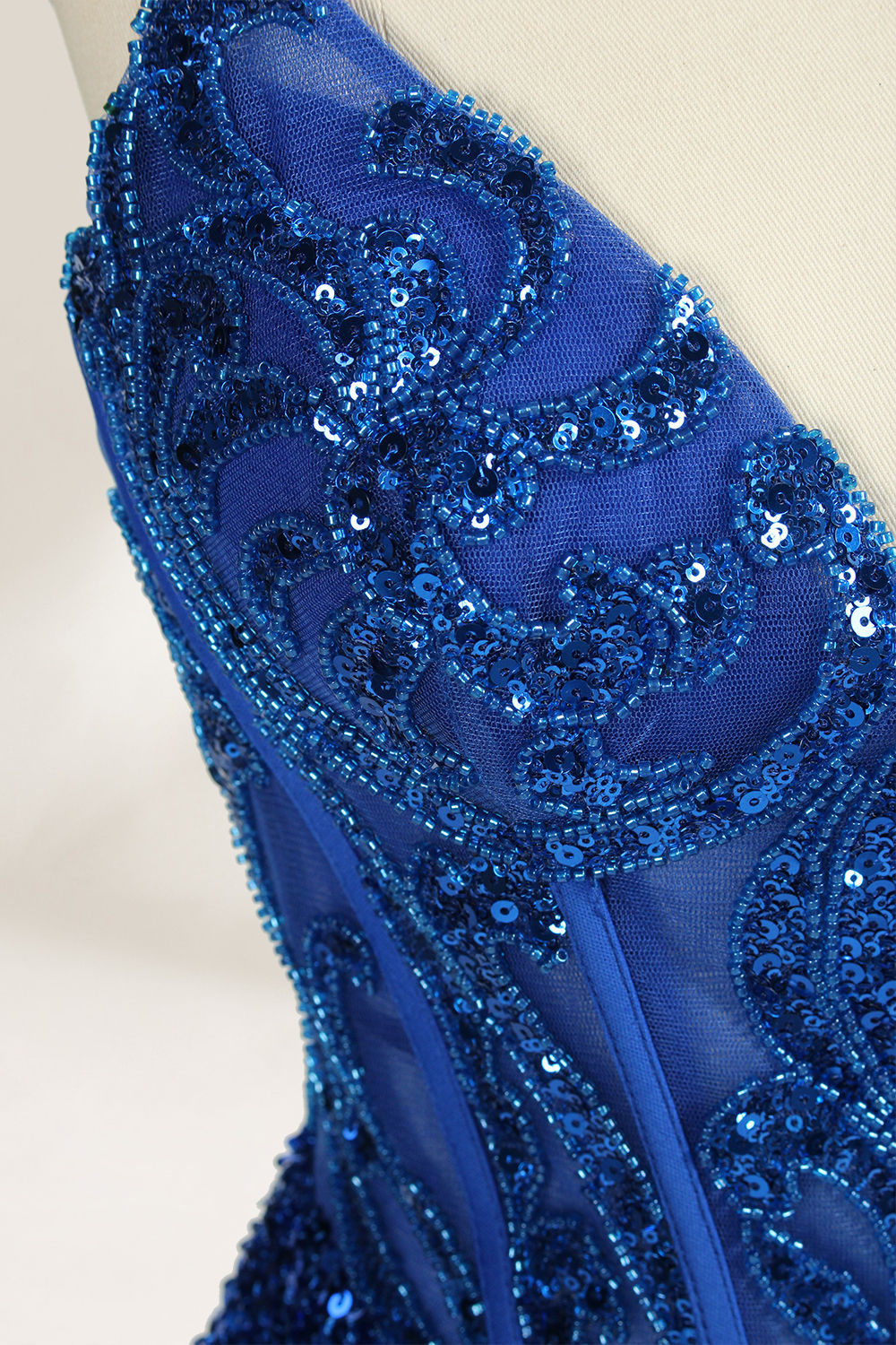 Set against a light background, a mannequin presents a blue gown adorned with sequins. It has thin straps, a deep V - neckline, and a mermaid - shaped skirt with a high side slit. The intricate sequin patterns and sheer bodice with embroidery add glamour, ideal for proms or formal dinners.8