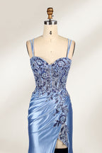 This photograph features a mannequin dressed in a luxurious, floor-length, light blue satin evening gown. The gown is intricately designed with delicate floral embroidery in silver and blue tones, primarily concentrated on the bodice and left hip. It has a plunging neckline and spaghetti straps, with a daring thigh-high slit on the left side. The mannequin is positioned against a plain, off-white background, allowing the gown's opulent texture and detailed craftsmanship to stand out. 6