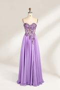 A photograph of a lavender, strapless, floor-length evening gown displayed on a dress form. The gown features intricate floral lace detailing on the bodice, transitioning into a flowing, chiffon skirt with a slight train. The dress form is positioned against a plain white background, emphasizing the gown's elegant and sophisticated design. The dress form has a wooden neck and shoulder structure with a small, round, black button at the top. The image captures the gown's luxurious texture and graceful .1