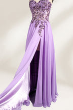 A photograph of a lavender, strapless, floor-length evening gown displayed on a dress form. The gown features intricate floral lace detailing on the bodice, transitioning into a flowing, chiffon skirt with a slight train. The dress form is positioned against a plain white background, emphasizing the gown's elegant and sophisticated design. The dress form has a wooden neck and shoulder structure with a small, round, black button at the top. The image captures the gown's luxurious texture and graceful .4