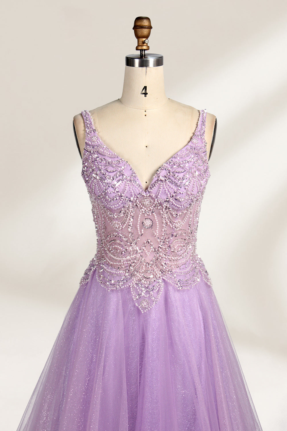 A mannequin showcases a lavender - purple tulle gown. It has a V - neck, beaded bodice, and a voluminous skirt. The elegant design, with intricate beadwork, suits formal events like galas or proms, radiating charm and grace.3
