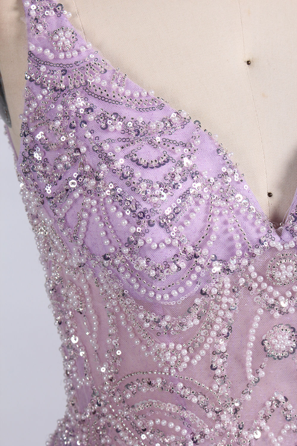 A mannequin showcases a lavender - purple tulle gown. It has a V - neck, beaded bodice, and a voluminous skirt. The elegant design, with intricate beadwork, suits formal events like galas or proms, radiating charm and grace.4