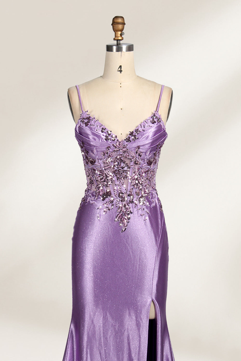 A mannequin showcases a lavender - purple satin gown. It has thin straps, a V - neck, floral - beaded bodice, and a high side slit. The elegant design, blending satin and intricate beadwork, suits formal events like galas or proms, radiating charm.3