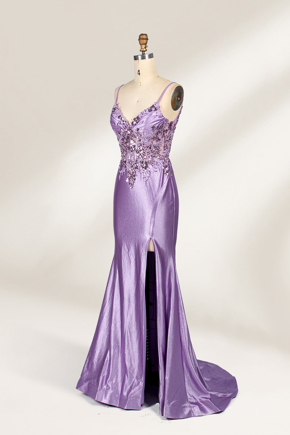 A mannequin showcases a lavender - purple satin gown. It has thin straps, a V - neck, floral - beaded bodice, and a high side slit. The elegant design, blending satin and intricate beadwork, suits formal events like galas or proms, radiating charm.5