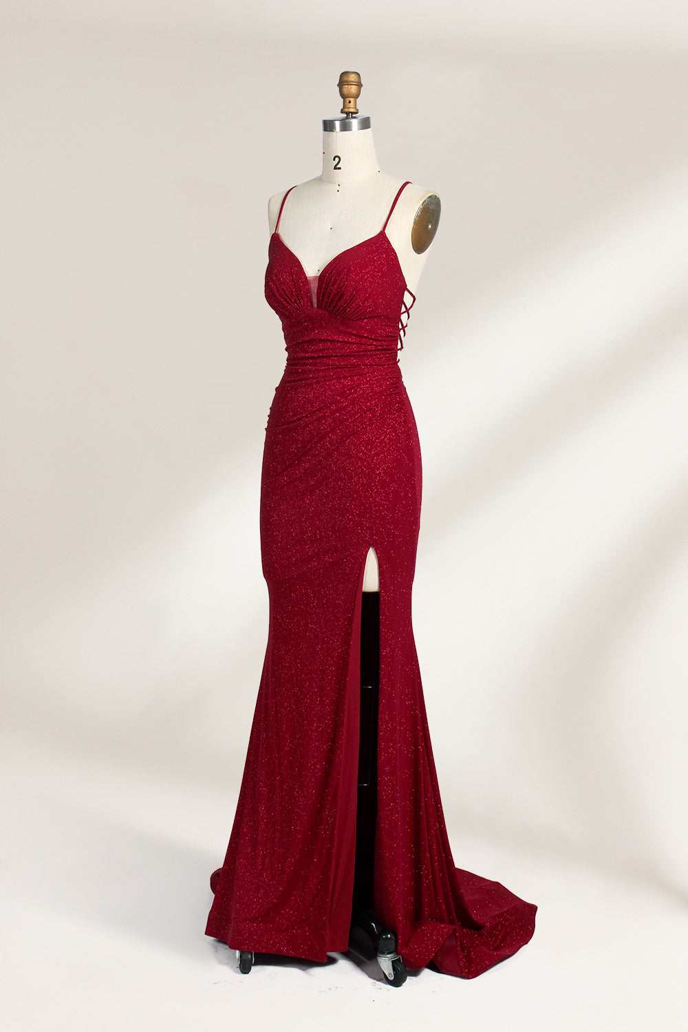 A mannequin showcases a royal - blue, glittery gown. It has thin straps, a ruched bodice, and a high side slit with a subtle train. The elegant design, with shimmering fabric, suits formal events like galas or proms, radiating sophistication.4