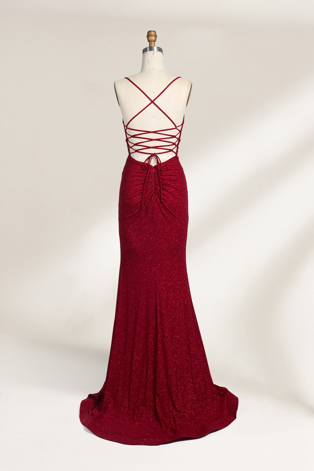 A mannequin showcases a royal - blue, glittery gown. It has thin straps, a ruched bodice, and a high side slit with a subtle train. The elegant design, with shimmering fabric, suits formal events like galas or proms, radiating sophistication.2