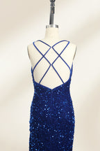 Photograph of a mannequin wearing a floor-length, deep V-neck, navy blue sequin dress with a high slit on the right side. The dress has a fitted bodice and a flared skirt. The background is a plain, light beige. The mannequin stands on a white pedestal, and the dress sparkles under soft, diffused lighting.05