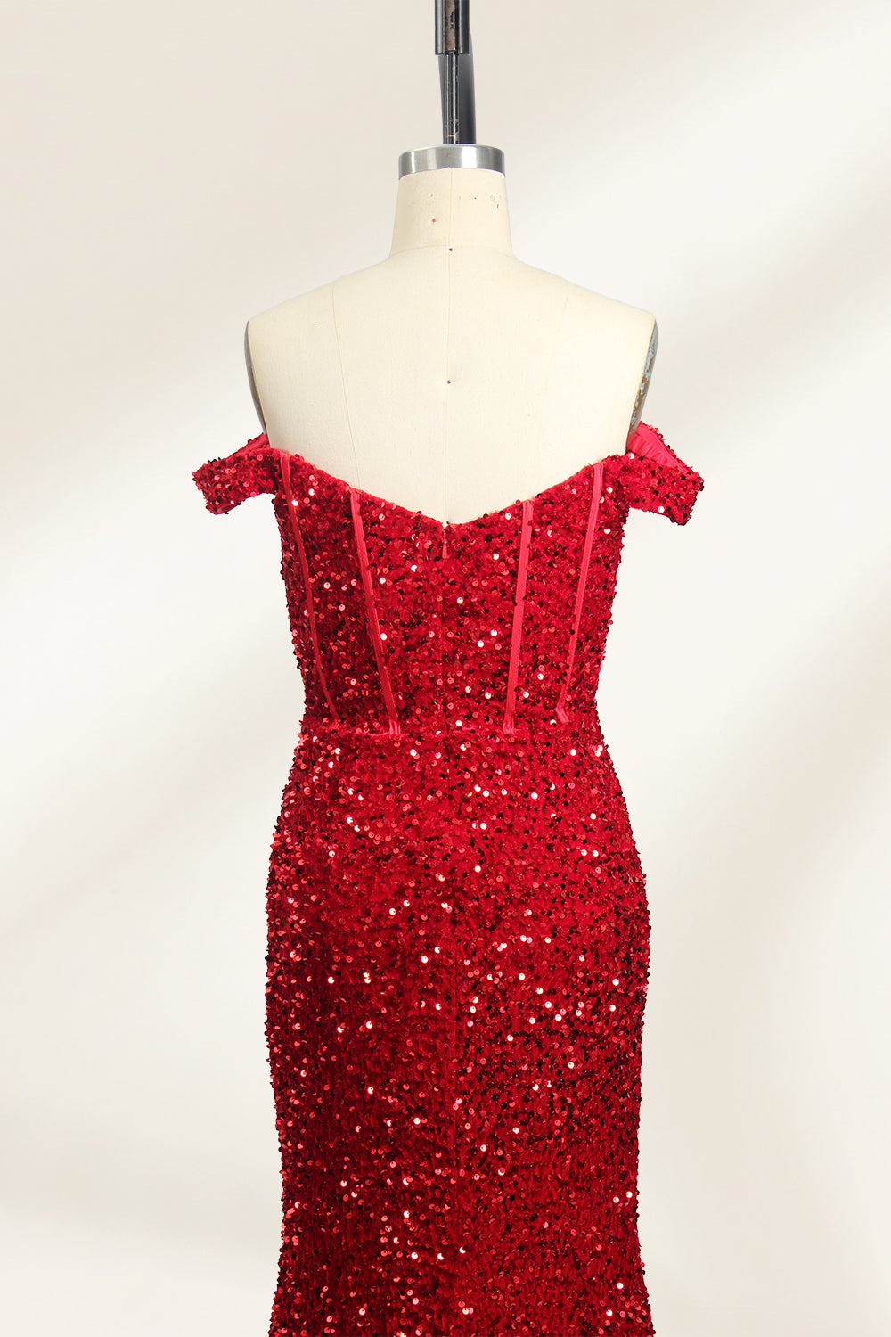A photograph of a mannequin showcasing an off-the-shoulder, floor-length red sequin gown with a plunging V-neckline. The dress has a fitted bodice and a flared skirt, creating a glamorous, elegant appearance. The mannequin stands against a plain white background, emphasizing the dress's vibrant color and intricate details.06
