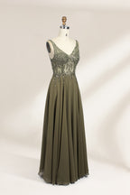 Photograph of an elegant, sleeveless, floor-length gown displayed on a dress form. The gown is a rich olive green with a fitted bodice adorned with intricate, sparkling embellishments. The neckline is a deep V, and the waistline is subtly cinched. The dress flows into a soft, gathered skirt. The background is a plain, light beige, enhancing the gown's luxurious texture and shimmering details.04