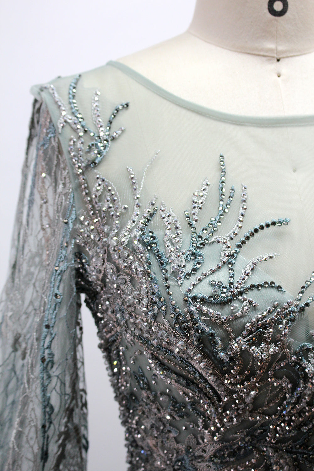 Presented on a mannequin is a deep - red evening gown. It features a sheer neckline, long billowy sleeves, and intricate gold - toned embroidery throughout. The elaborate design gives off a luxurious and elegant vibe, ideal for formal occasions.8