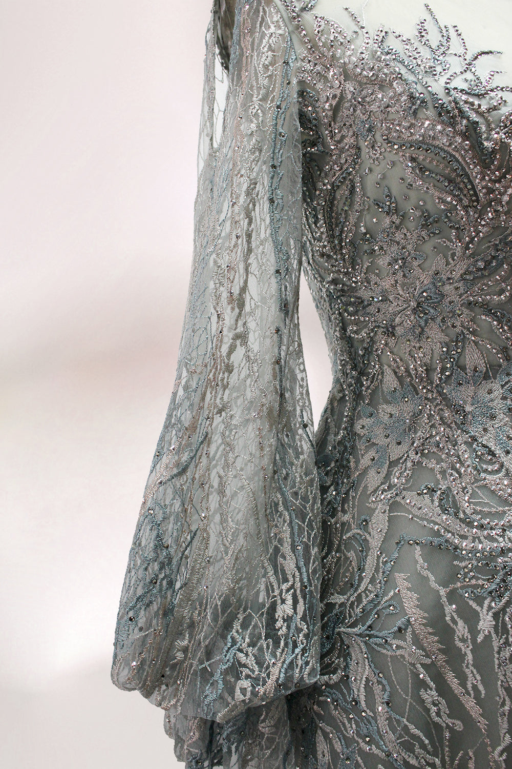 Presented on a mannequin is a deep - red evening gown. It features a sheer neckline, long billowy sleeves, and intricate gold - toned embroidery throughout. The elaborate design gives off a luxurious and elegant vibe, ideal for formal occasions.9