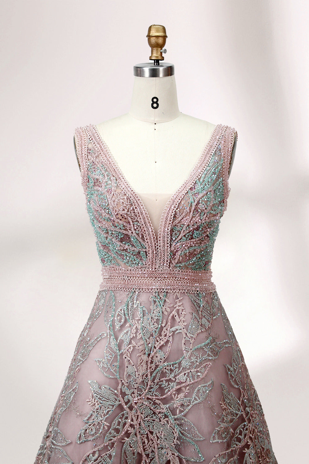Displayed on a mannequin is a pink - hued evening gown. It features a deep V - neckline, intricate floral embroidery in shades of blue and pink, and a flowing skirt. The elegant design creates a romantic and sophisticated look, perfect for formal events.2