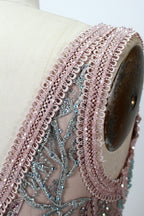 Displayed on a mannequin is a pink - hued evening gown. It features a deep V - neckline, intricate floral embroidery in shades of blue and pink, and a flowing skirt. The elegant design creates a romantic and sophisticated look, perfect for formal events.7