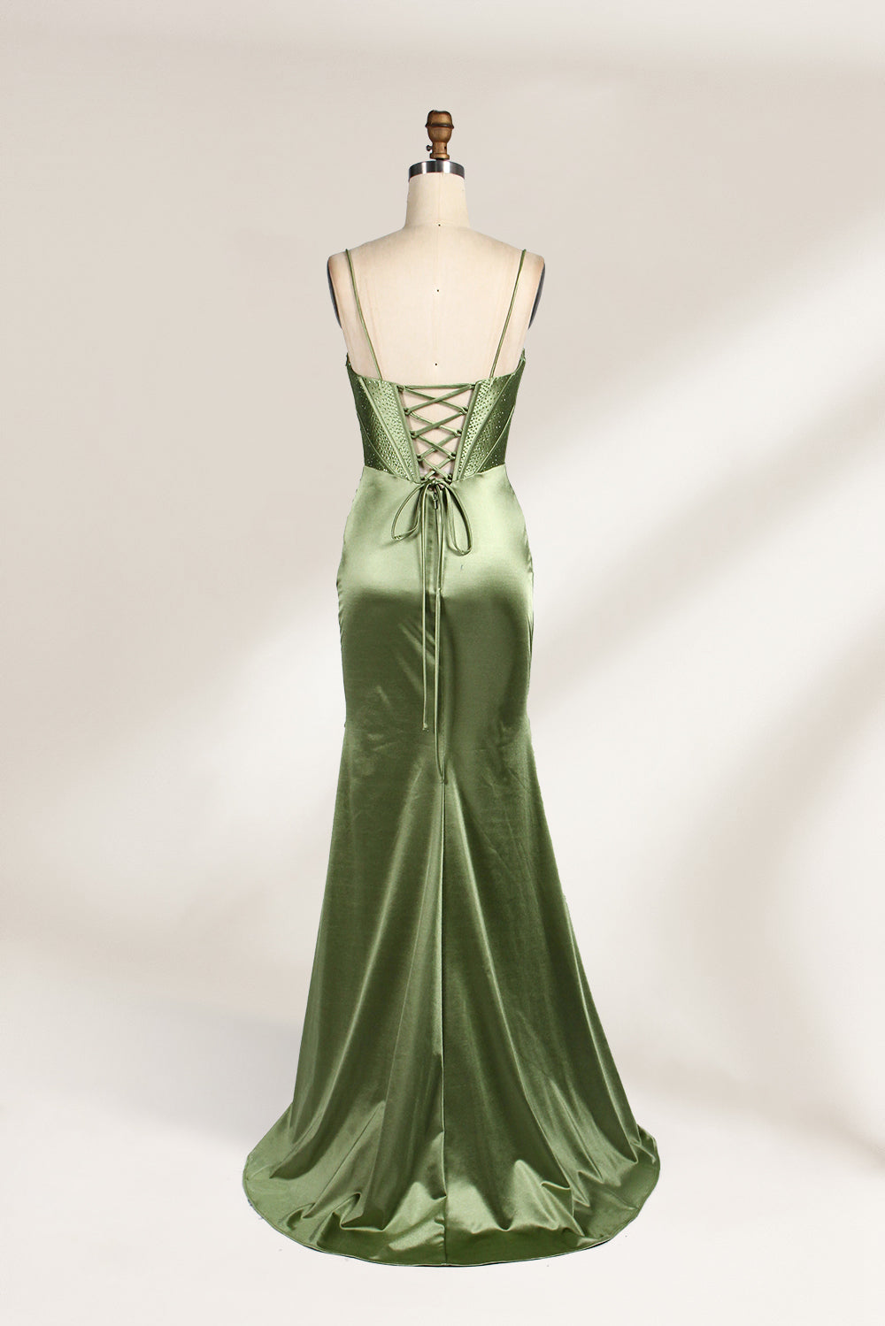 A mannequin showcases an olive - green satin gown. It has thin straps, a deep V - neck, ruched bodice, and a high side slit with sheer details. The elegant design, blending satin and intricate ruching, suits formal events like galas or proms, radiating sophistication.6