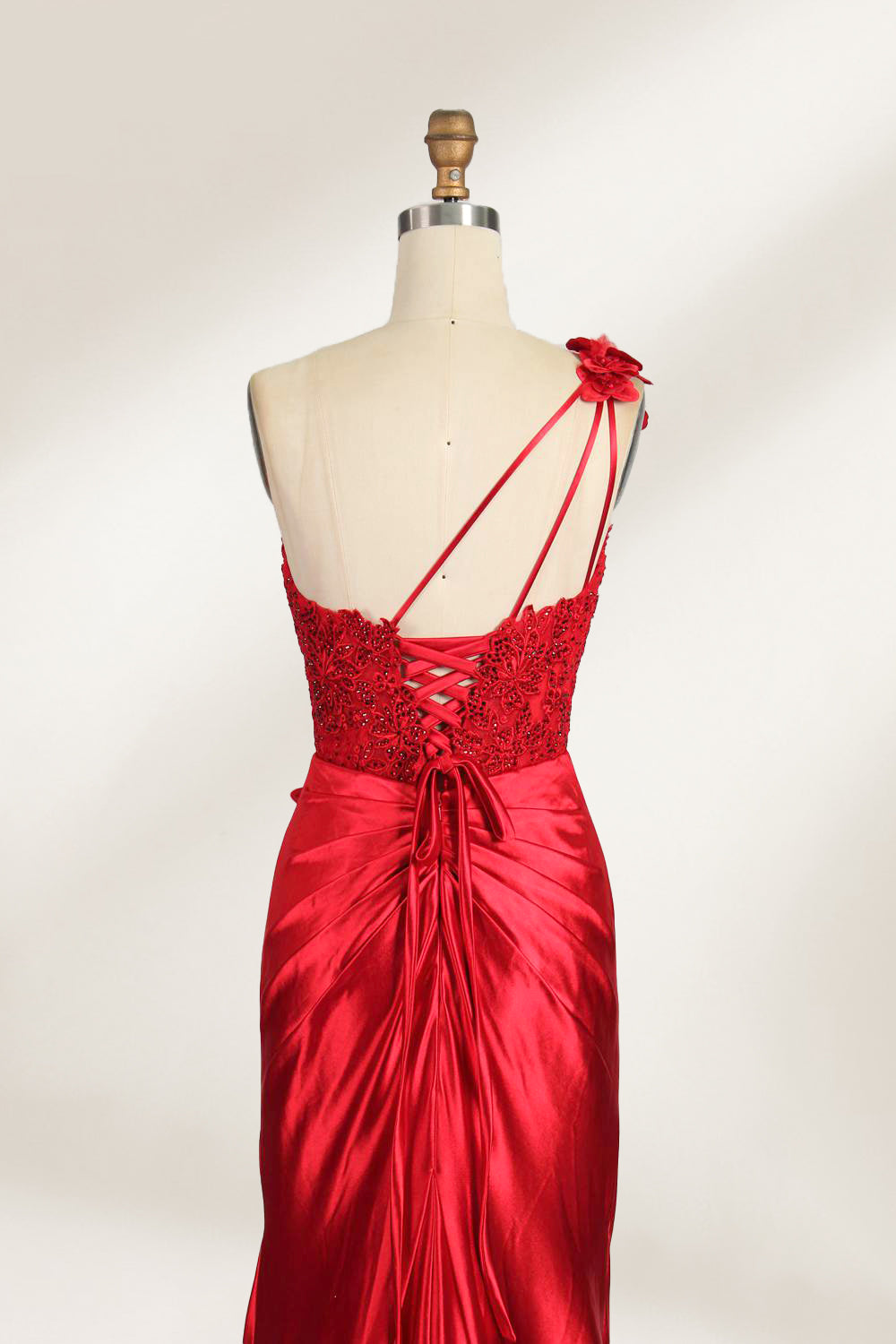 A mannequin displays a teal satin gown. It features a deep V - neckline with lace embroidery on the bodice, a ruched skirt, and a mermaid silhouette. The elegant details and shiny fabric create a glamorous look, perfect for formal events like proms or galas.10