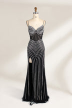 A mannequin showcases a black gown with silver beading. It has thin straps, a sheer bodice, and a high side slit. The geometric beading pattern adds glamour, making it perfect for formal events like galas or proms, radiating sophistication.1