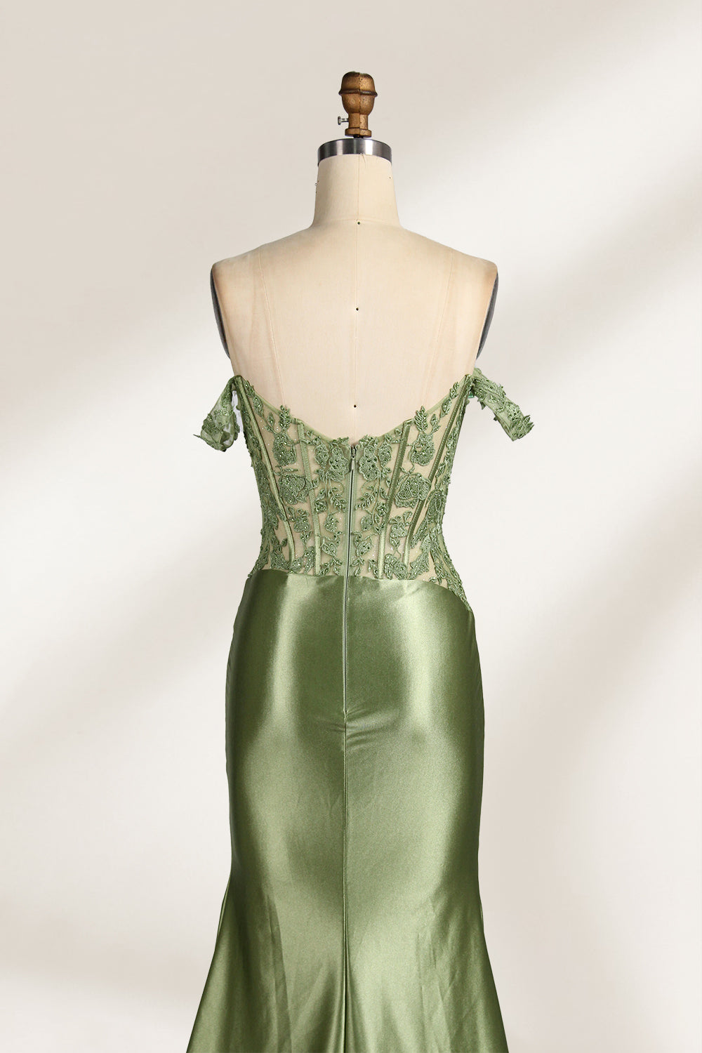 A mannequin showcases an olive - green gown. It has off - the - shoulder, lace - detailed sleeves, a sheer bodice with floral embroidery, and a high side slit. The elegant design, blending satin and lace, suits formal events like galas, radiating charm.4