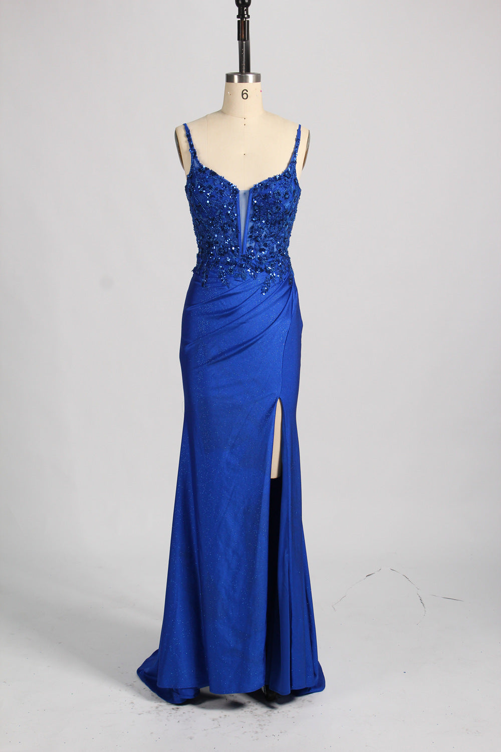 A woman with sleek dark hair and a poised stance wears a red, glittery gown. It has thin straps, beaded bodice, and a high side slit. Paired with silver heels, the outfit radiates elegance, perfect for formal events like galas, blending glamour and style.
8
