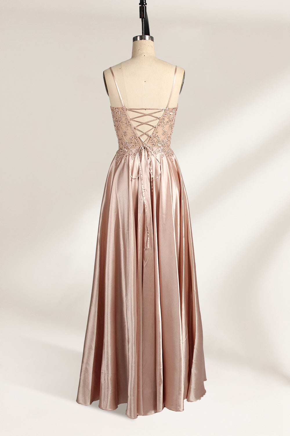 A mannequin showcases a champagne - satin gown. It has thin straps, a sheer lace - detailed bodice, and a voluminous skirt. The elegant design, blending satin and intricate lace, suits formal events like weddings, radiating sophistication.4