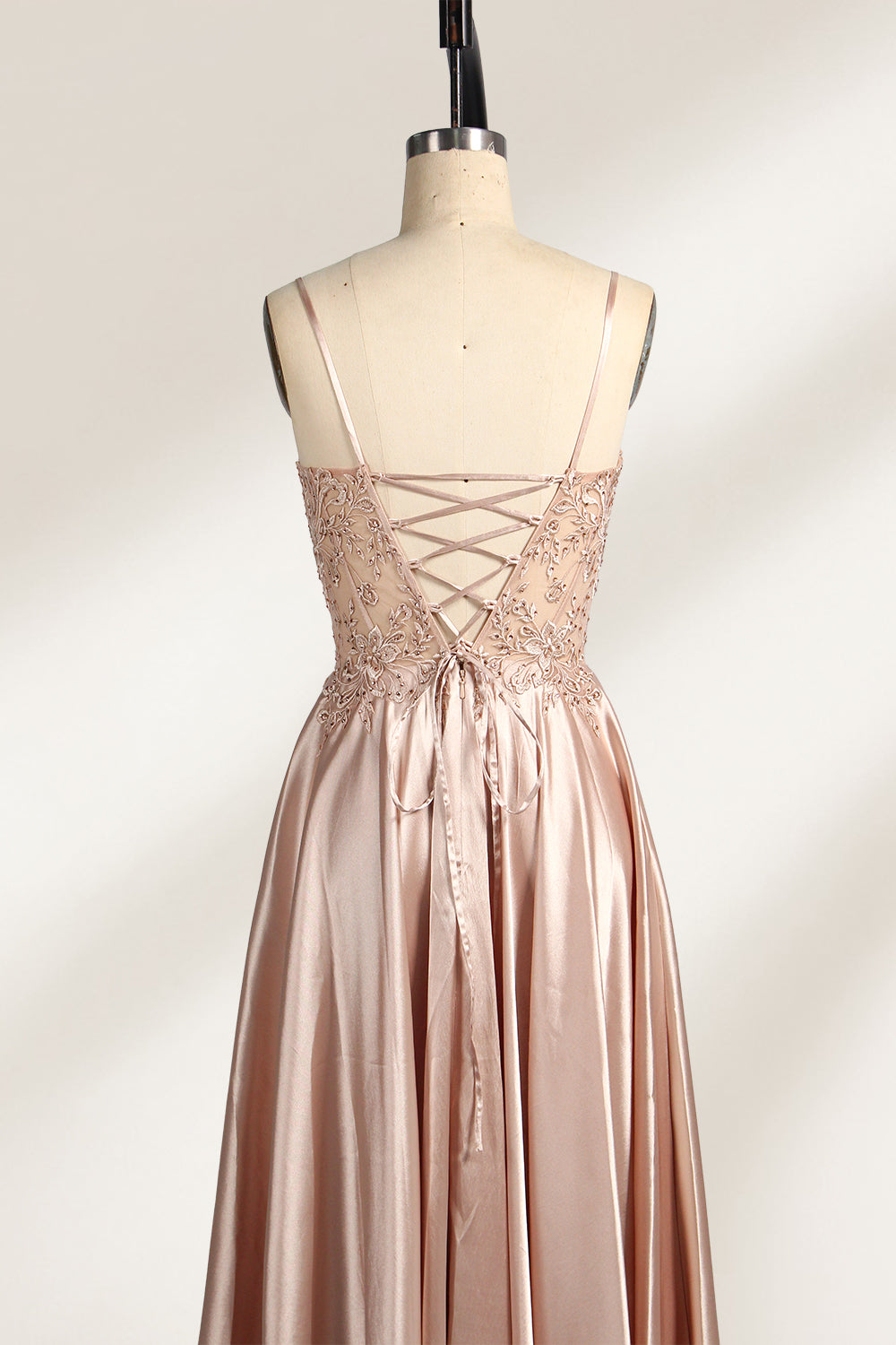 A mannequin showcases a champagne - satin gown. It has thin straps, a sheer lace - detailed bodice, and a voluminous skirt. The elegant design, blending satin and intricate lace, suits formal events like weddings, radiating sophistication.5