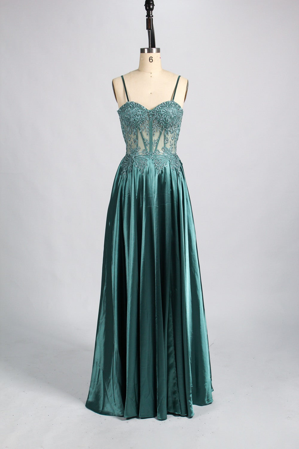 A mannequin showcases a champagne - satin gown. It has thin straps, a sheer lace - detailed bodice, and a voluminous skirt. The elegant design, blending satin and intricate lace, suits formal events like weddings, radiating sophistication.7