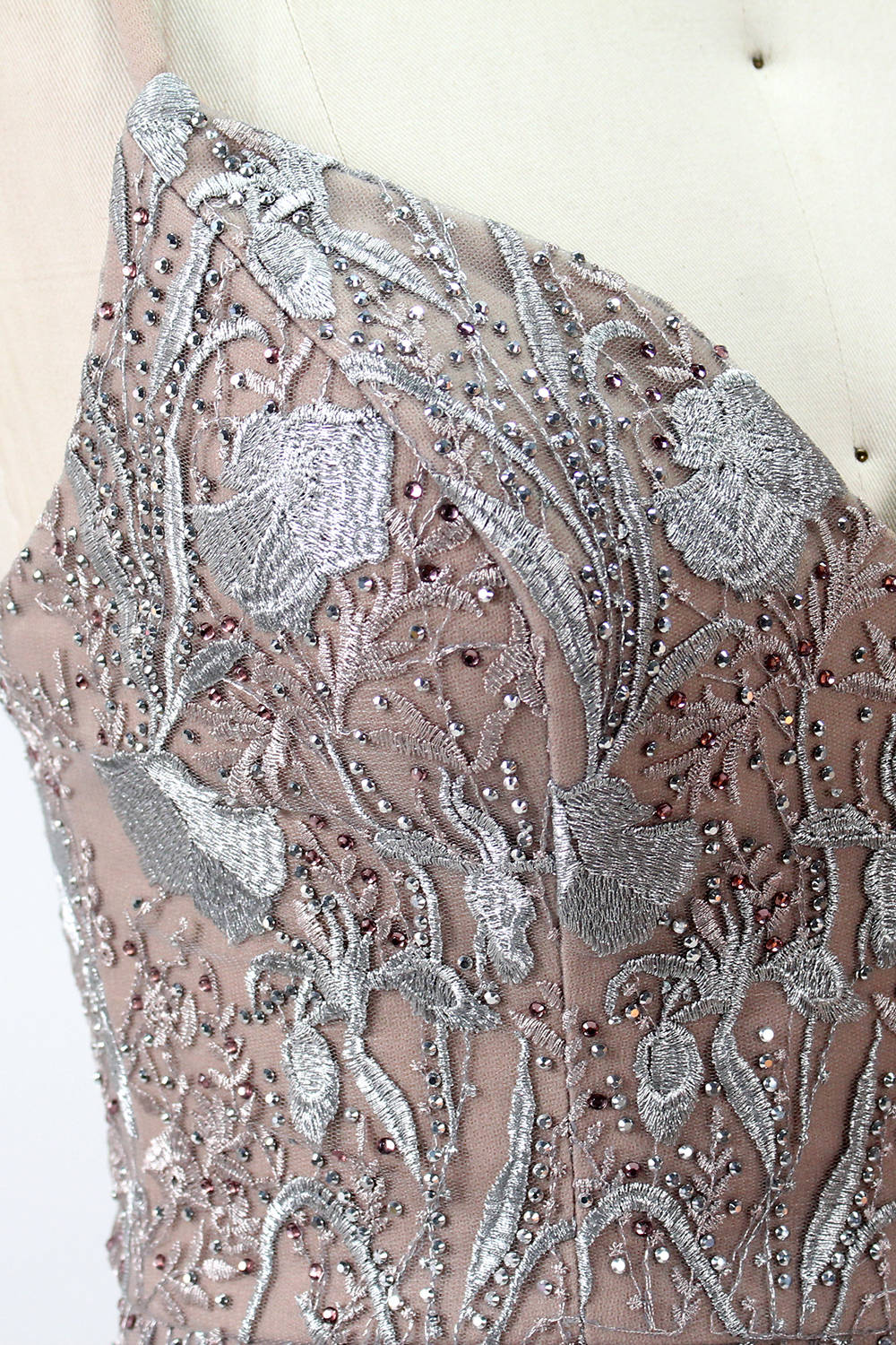 Showcased on a mannequin is a taupe - toned mermaid - cut gown. It has thin straps, a sweetheart neckline, and is embellished with delicate silver floral embroidery all over, plus a flowing tulle skirt. The refined design gives off a glamorous aura, ideal for formal events such as proms or weddings.7
