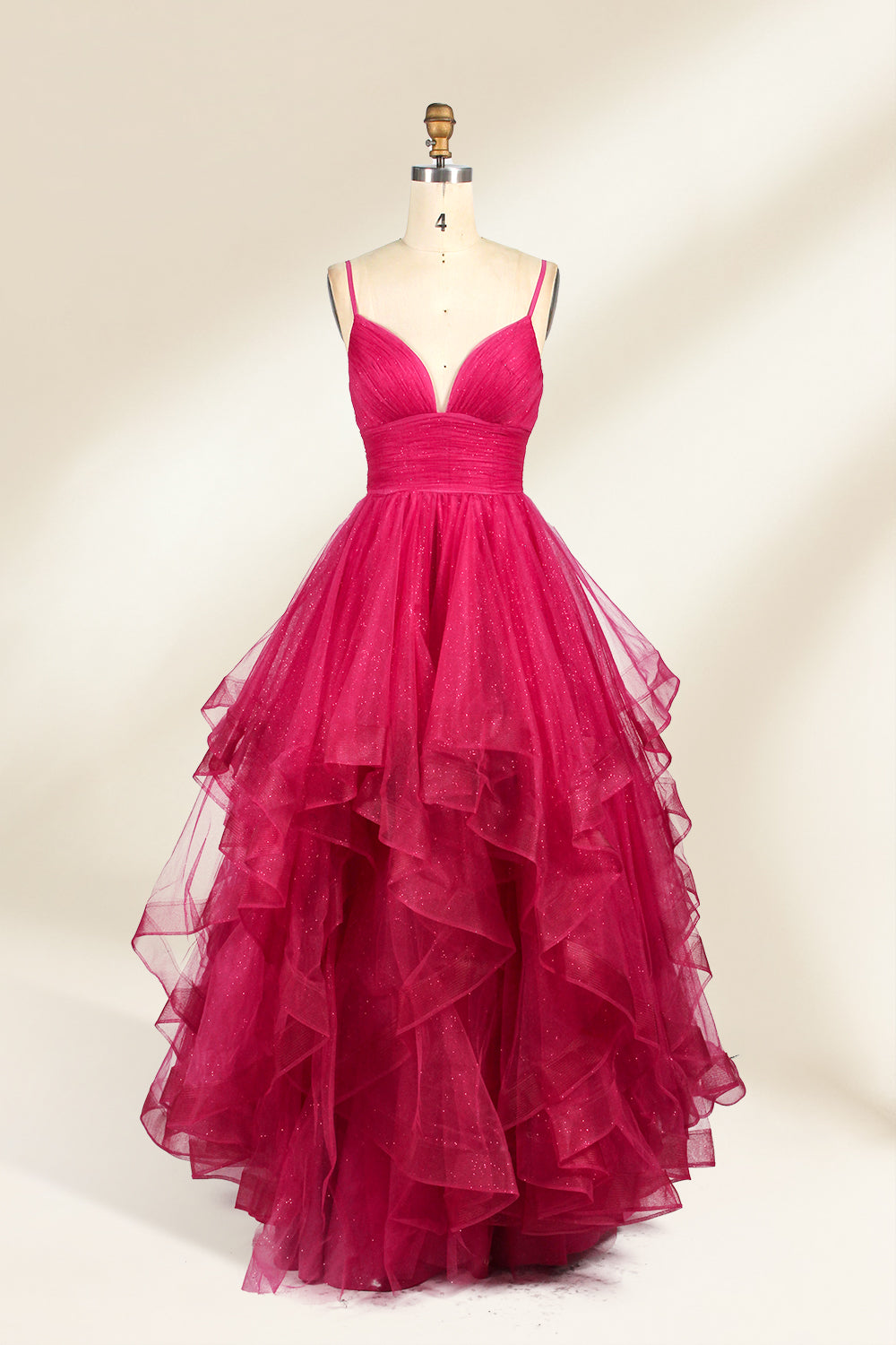 A mannequin showcases a magenta - tulle gown. It has thin straps, a V - neck, and tiered, ruffled skirt. The sparkling tulle and layered design add romance, perfect for formal events like proms, radiating glamour.1