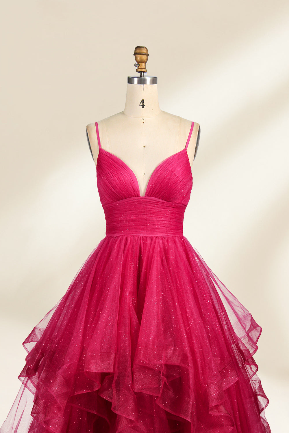 A mannequin showcases a magenta - tulle gown. It has thin straps, a V - neck, and tiered, ruffled skirt. The sparkling tulle and layered design add romance, perfect for formal events like proms, radiating glamour.3