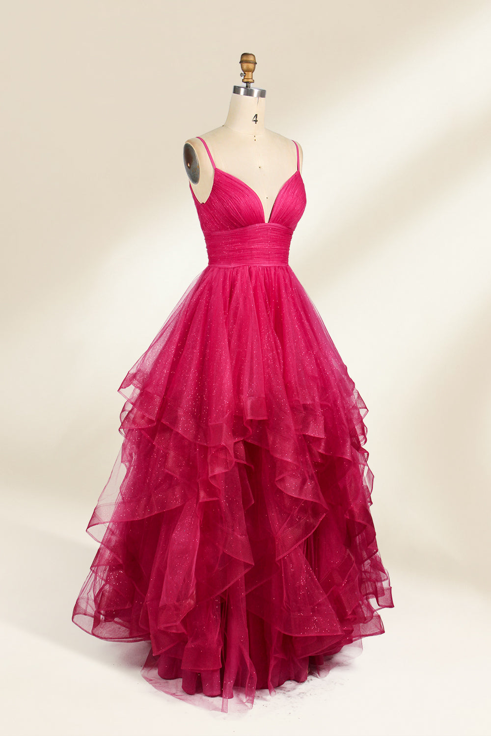 A mannequin showcases a magenta - tulle gown. It has thin straps, a V - neck, and tiered, ruffled skirt. The sparkling tulle and layered design add romance, perfect for formal events like proms, radiating glamour.4