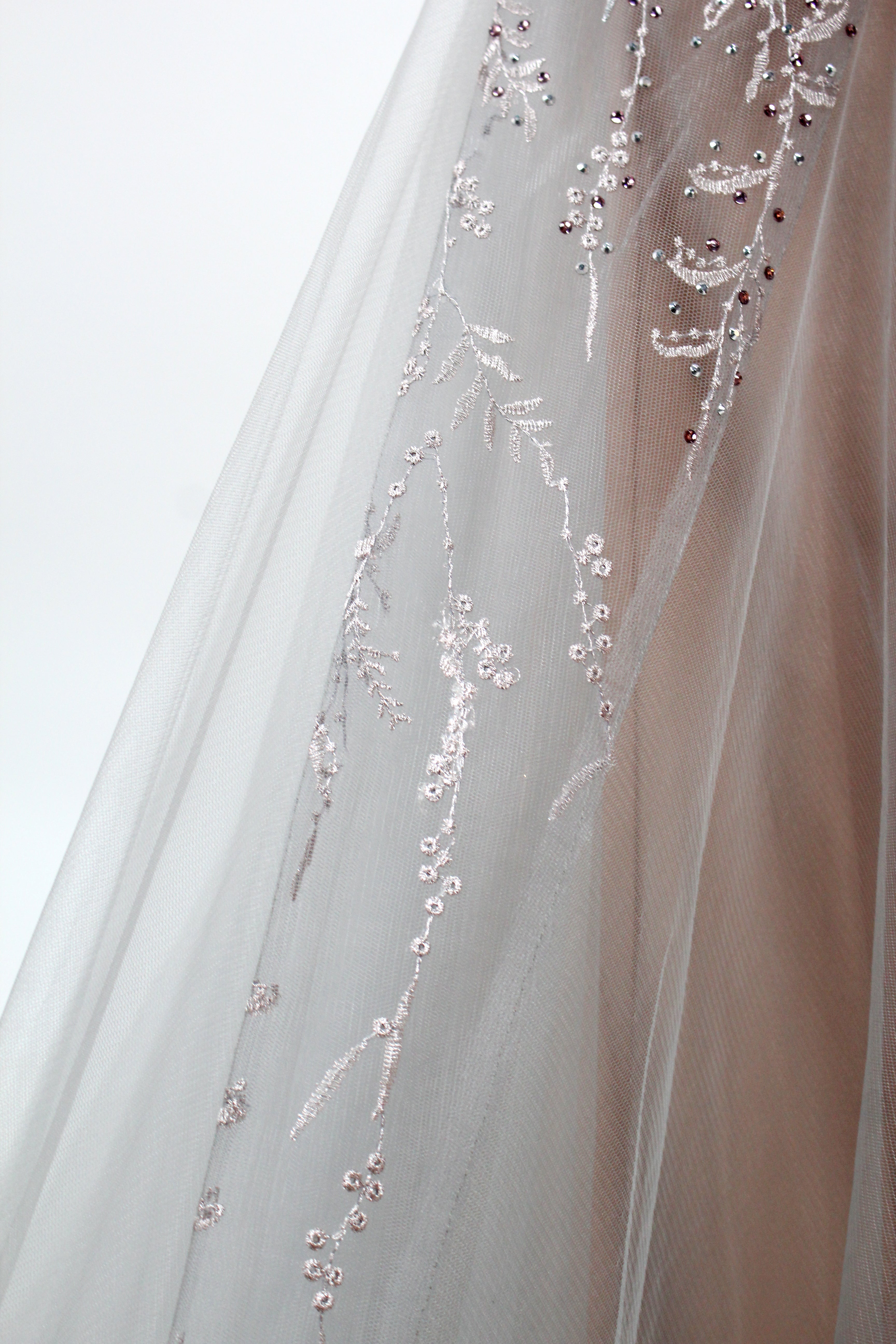 Showcased on a mannequin is a taupe - toned mermaid - cut gown. It has thin straps, a sweetheart neckline, and is embellished with delicate silver floral embroidery all over, plus a flowing tulle skirt. The refined design gives off a glamorous aura, ideal for formal events such as proms or weddings.6 