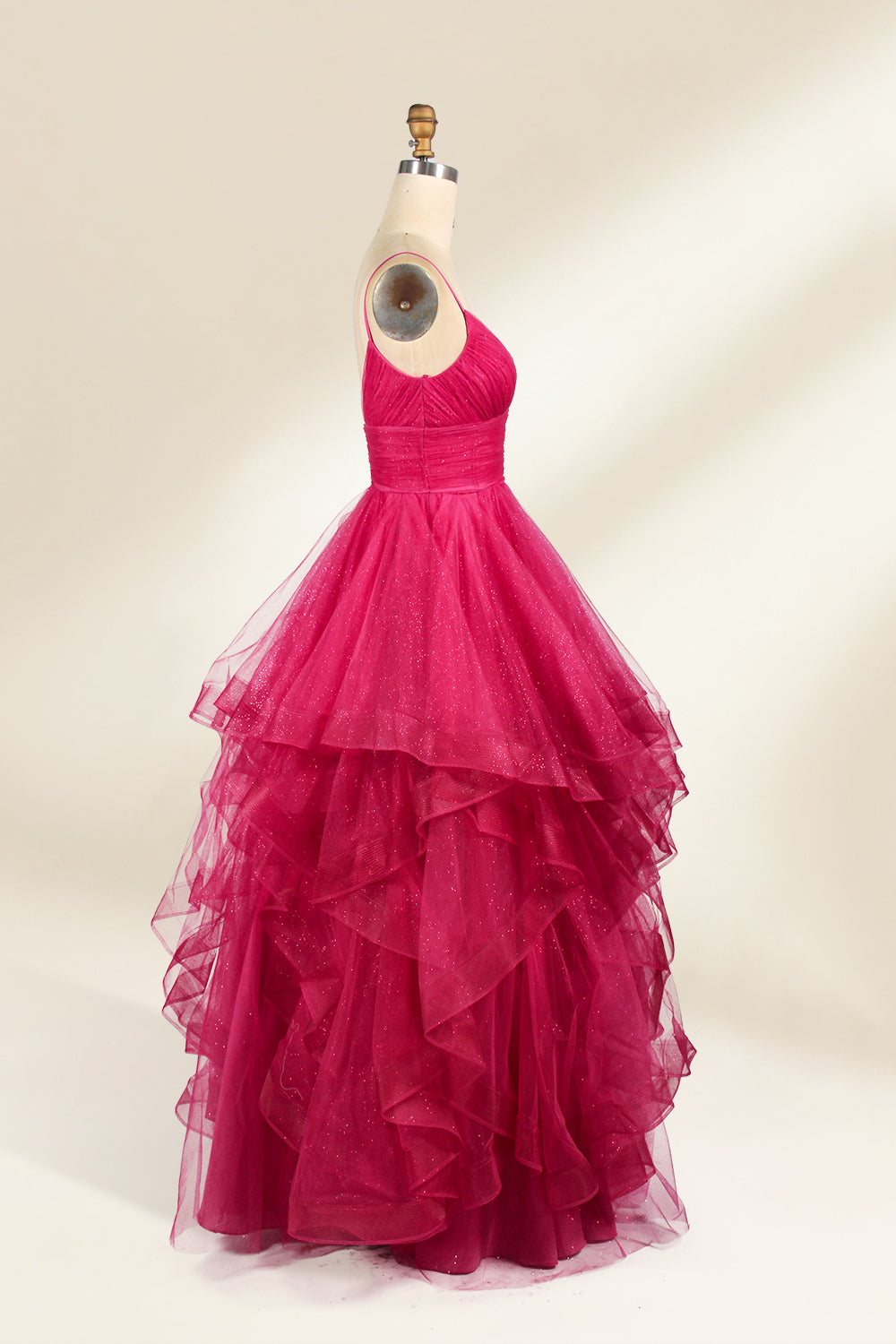 A mannequin showcases a magenta - tulle gown. It has thin straps, a V - neck, and tiered, ruffled skirt. The sparkling tulle and layered design add romance, perfect for formal events like proms, radiating glamour.5