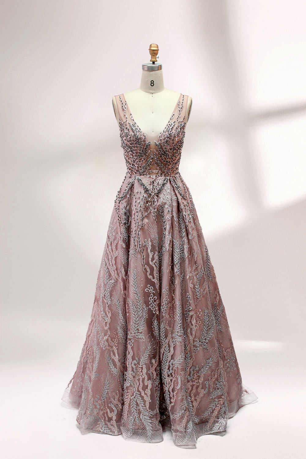 Presented on a mannequin is a mauve evening gown. It features a deep V - neckline, intricate floral embroidery with bead accents, and a flowing skirt. The elegant design creates a romantic and sophisticated look, perfect for formal events.1