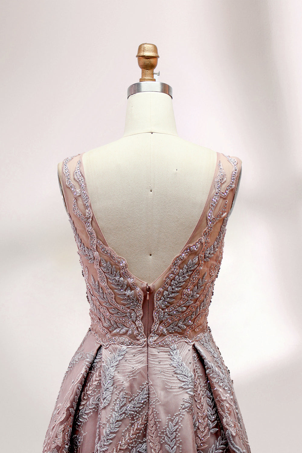 Presented on a mannequin is a mauve evening gown. It features a deep V - neckline, intricate floral embroidery with bead accents, and a flowing skirt. The elegant design creates a romantic and sophisticated look, perfect for formal events.5