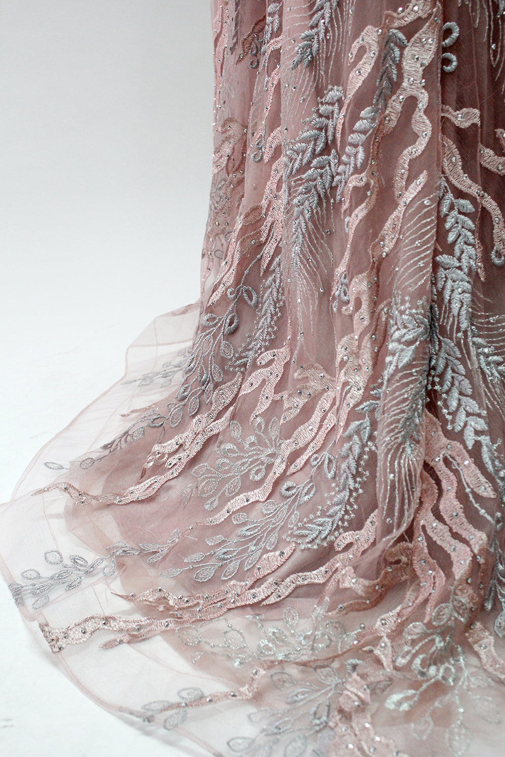 Presented on a mannequin is a mauve evening gown. It features a deep V - neckline, intricate floral embroidery with bead accents, and a flowing skirt. The elegant design creates a romantic and sophisticated look, perfect for formal events.8