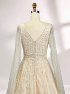 Against a light - hued background, a woman wears an ivory sequin gown with a sheer cape. It features a deep V - neckline, a fitted bodice, and a voluminous skirt. The shimmering sequins and elegant cape design radiate sophistication, perfect for formal events like charity balls, exuding a regal aura.6