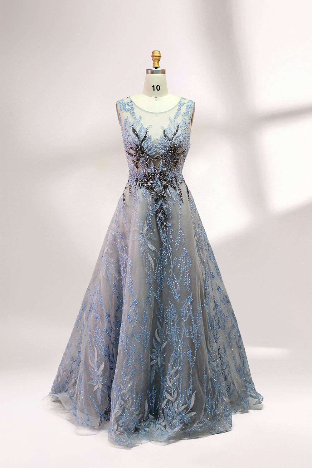 Presented on a mannequin is a gown with a gray base and rich red floral embroidery. It features a sheer neckline, a sleeveless design, and an intricate pattern that gives off a romantic and elegant vibe, perfect for formal events.3
