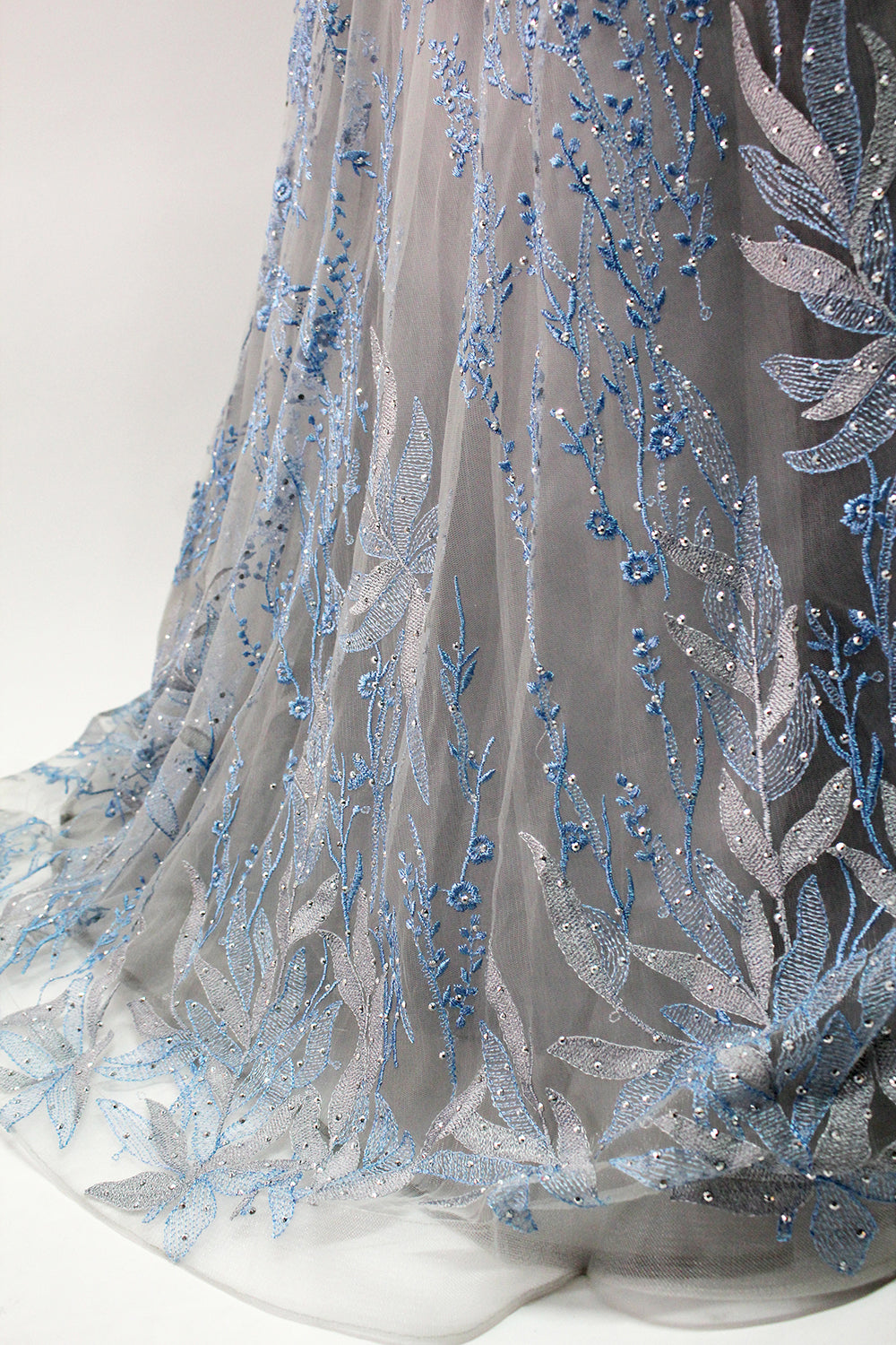Presented on a mannequin is a gown with a gray base and rich red floral embroidery. It features a sheer neckline, a sleeveless design, and an intricate pattern that gives off a romantic and elegant vibe, perfect for formal events.8