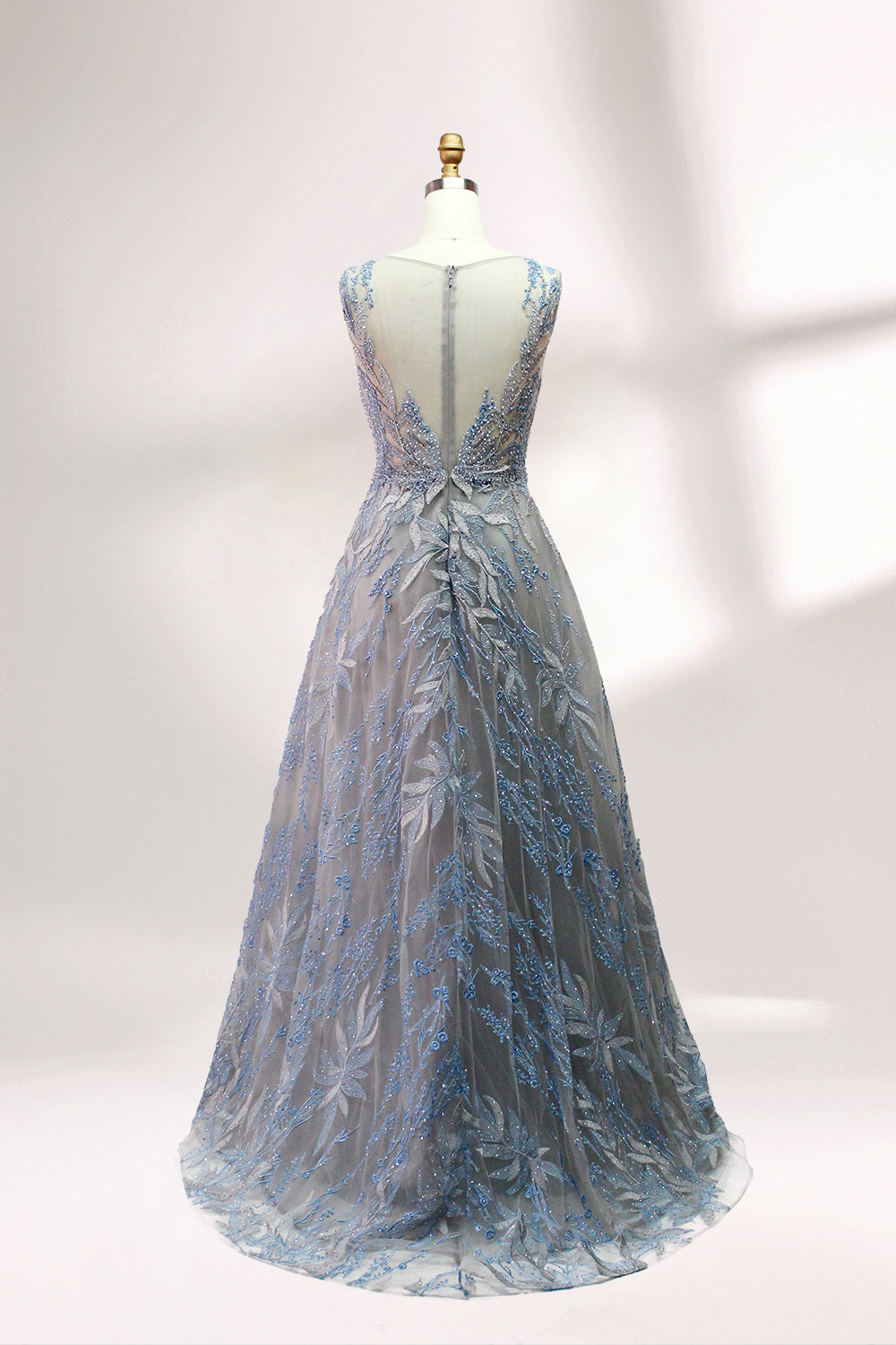 Presented on a mannequin is a gown with a gray base and rich red floral embroidery. It features a sheer neckline, a sleeveless design, and an intricate pattern that gives off a romantic and elegant vibe, perfect for formal events.2
