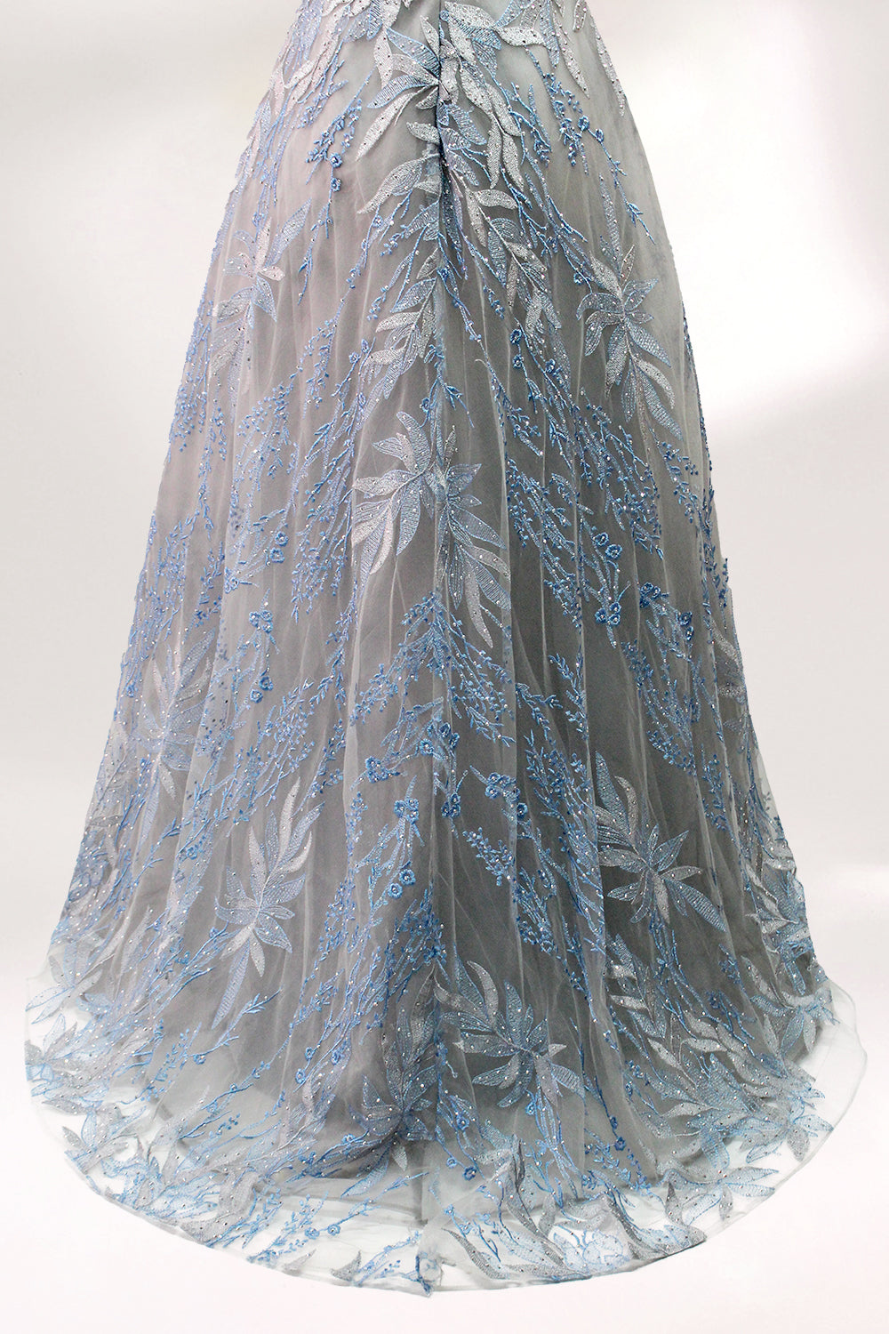 Presented on a mannequin is a gown with a gray base and rich red floral embroidery. It features a sheer neckline, a sleeveless design, and an intricate pattern that gives off a romantic and elegant vibe, perfect for formal events.9