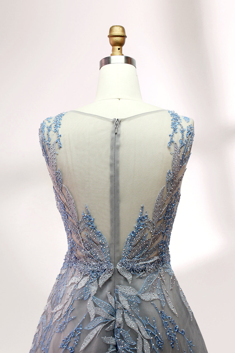 Presented on a mannequin is a gown with a gray base and rich red floral embroidery. It features a sheer neckline, a sleeveless design, and an intricate pattern that gives off a romantic and elegant vibe, perfect for formal events.10