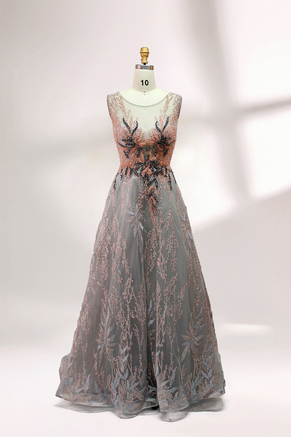 Presented on a mannequin is a gown with a gray base and rich red floral embroidery. It features a sheer neckline, a sleeveless design, and an intricate pattern that gives off a romantic and elegant vibe, perfect for formal events.4
