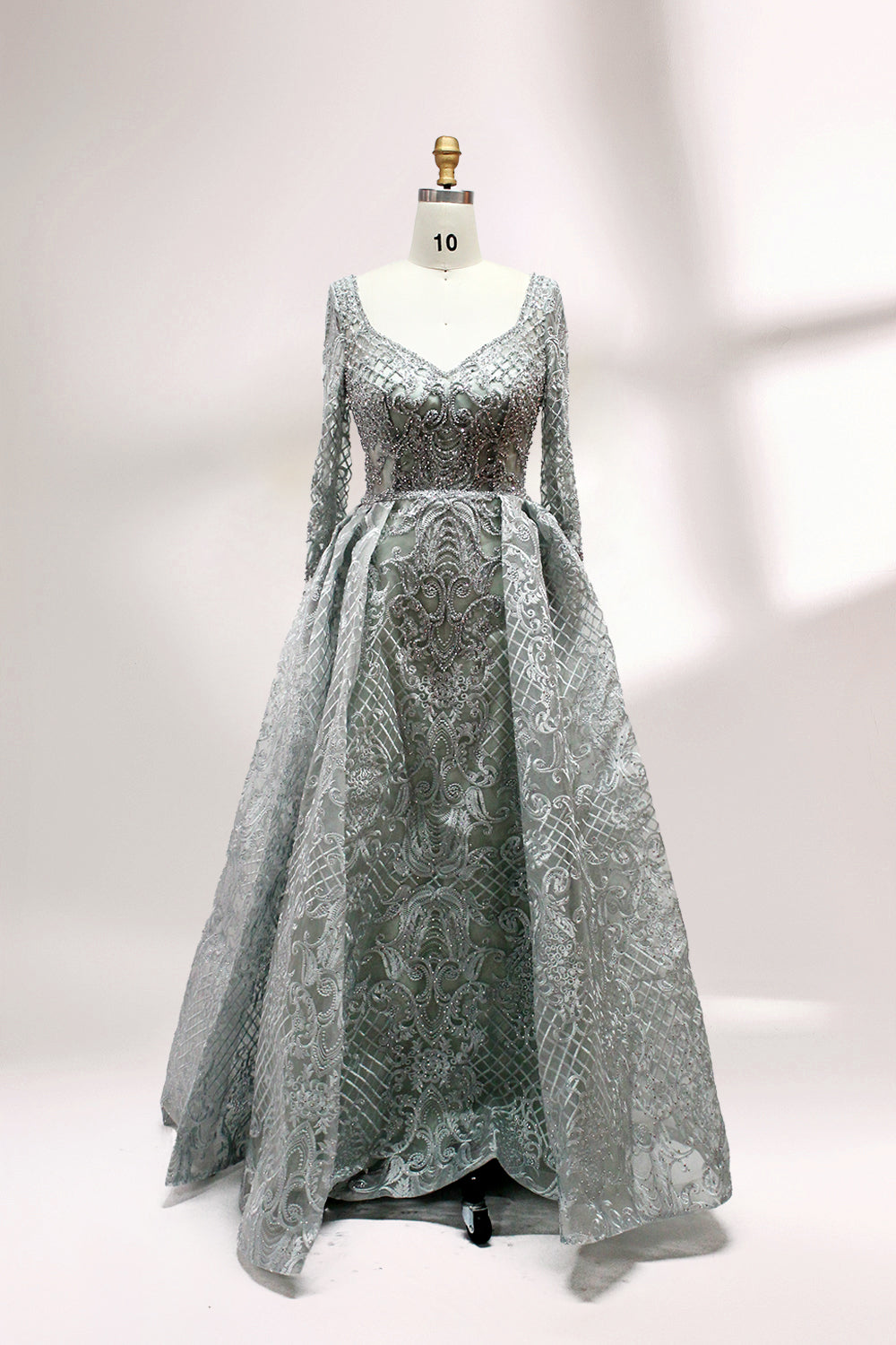 Showcased on a mannequin is a silver - gray evening gown. It has a V - neckline, long sleeves, and intricate lace embroidery all over. The elaborate design gives off a luxurious and elegant vibe, ideal for formal occasions.1