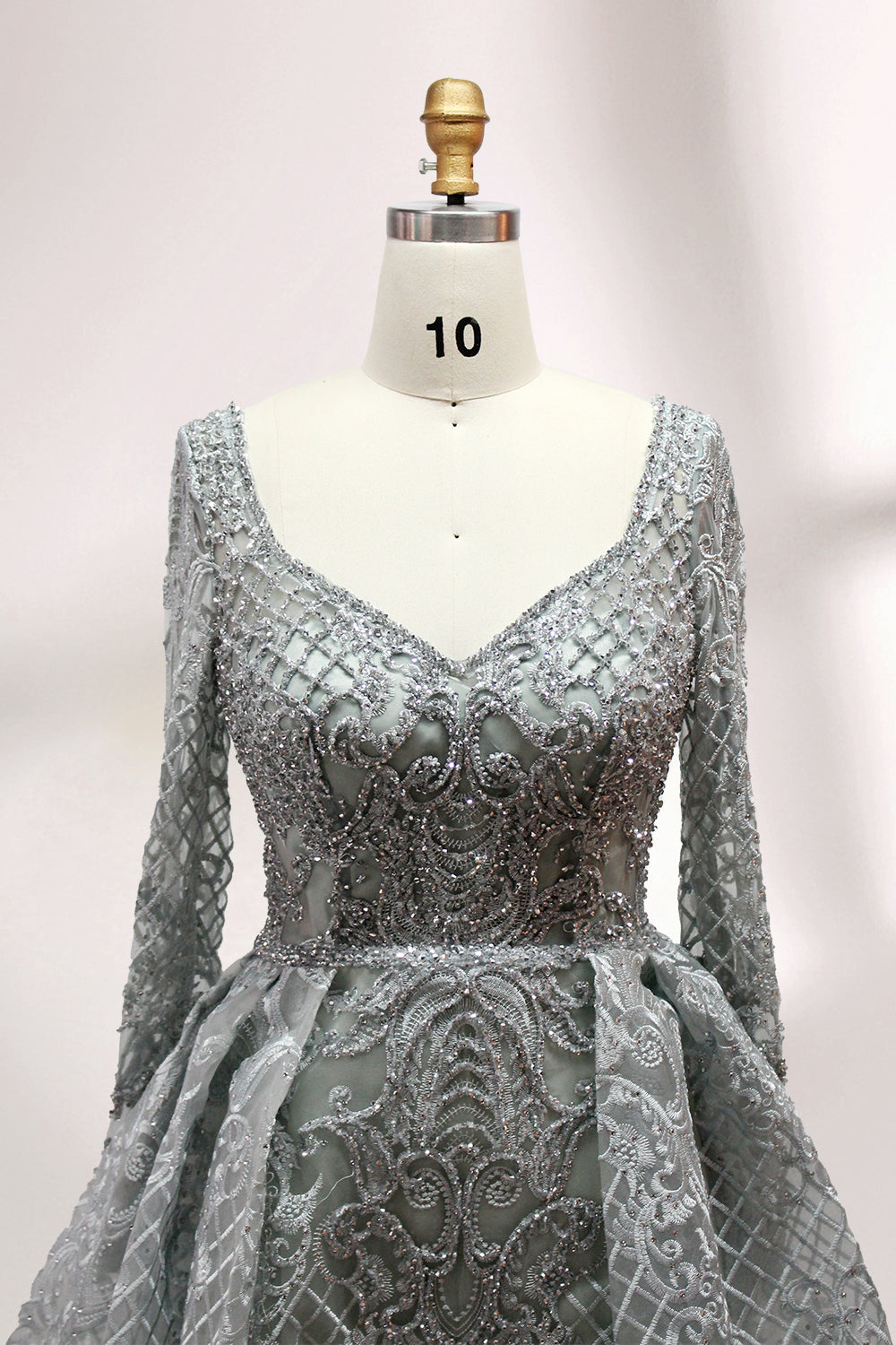 Showcased on a mannequin is a silver - gray evening gown. It has a V - neckline, long sleeves, and intricate lace embroidery all over. The elaborate design gives off a luxurious and elegant vibe, ideal for formal occasions.5