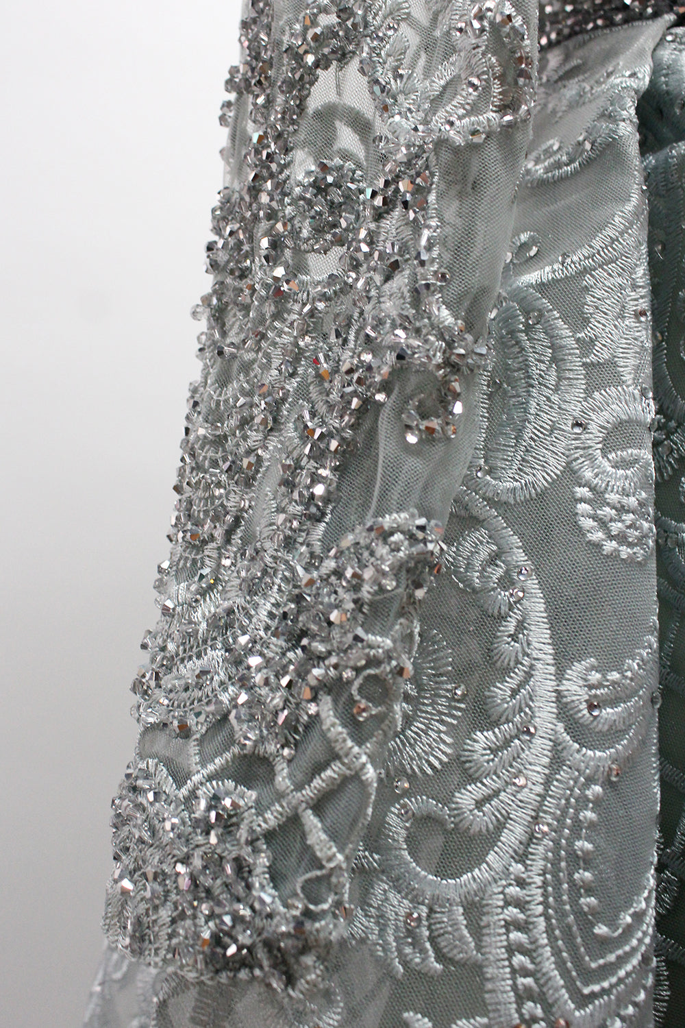 Showcased on a mannequin is a silver - gray evening gown. It has a V - neckline, long sleeves, and intricate lace embroidery all over. The elaborate design gives off a luxurious and elegant vibe, ideal for formal occasions.10