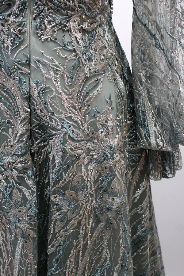 Presented on a mannequin is a deep - red evening gown. It features a sheer neckline, long billowy sleeves, and intricate gold - toned embroidery throughout. The elaborate design gives off a luxurious and elegant vibe, ideal for formal occasions.7