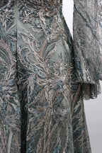 Presented on a mannequin is a deep - red evening gown. It features a sheer neckline, long billowy sleeves, and intricate gold - toned embroidery throughout. The elaborate design gives off a luxurious and elegant vibe, ideal for formal occasions.7
