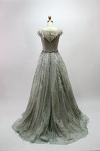 Displayed on a mannequin is a light - green evening gown. It features a sheer neckline with feather and bead embellishments, and a voluminous, glittering skirt. The elegant design creates a dreamy and luxurious look, perfect for formal events.3