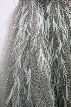 Displayed on a mannequin is a light - green evening gown. It features a sheer neckline with feather and bead embellishments, and a voluminous, glittering skirt. The elegant design creates a dreamy and luxurious look, perfect for formal events.7